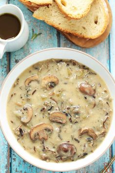 a white bowl filled with mushroom soup next to slices of bread