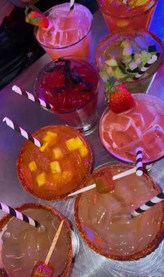 several drinks are lined up on a table with strawberries and fruit in cups next to each other