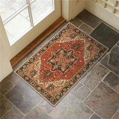 an orange and black rug on the floor in front of a door with two windows