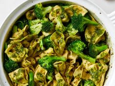 a bowl filled with pasta and broccoli on top of a white tablecloth