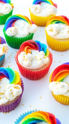 rainbow cupcakes with white frosting and sprinkles are arranged on a table