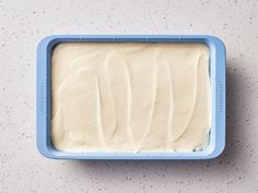 a blue container filled with white frosting on top of a counter