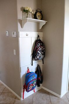 there is a coat rack with backpacks hanging on it and a clock in the corner