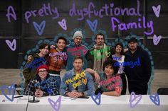 a group of people standing around a table with signs on it that say pretty diffctional family