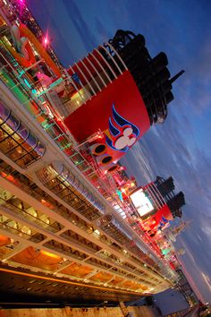 a cruise ship is lit up at night with colorful lights on it's sides