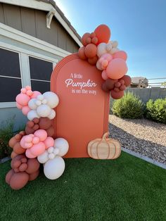 an orange and white balloon arch with pumpkins on it in front of a house