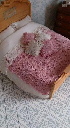 a bed with a pink blanket on top of it next to a night stand and dresser