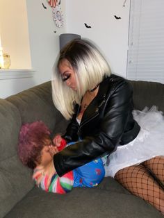 a woman with white hair is sitting on a couch next to a small child wearing fishnet stockings