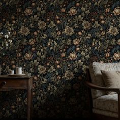 a chair sitting in front of a wallpapered with flowers and leaves on it