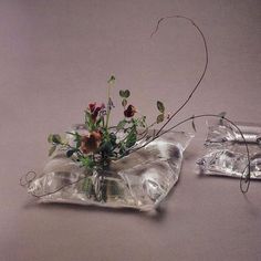 two clear vases with flowers in them on a table