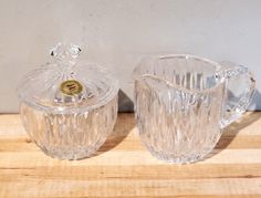 two clear glass dishes sitting on top of a wooden table next to each other,