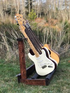 an electric guitar sits on a stand in the grass