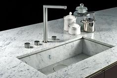 a marble sink and faucet with soap dispenser on the counter