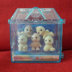 four small toy animals in a clear plastic box on a red cloth background with the words syjurian families written below them