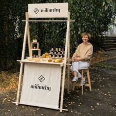 a woman sitting in front of a stand with food on it