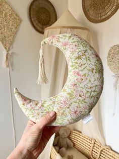 a person holding up a decorative crescent shaped pillow