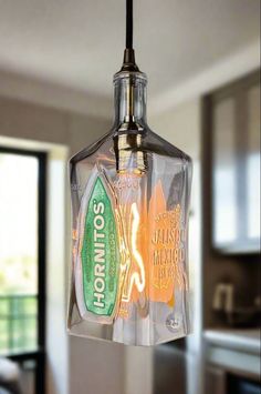 a glass bottle hanging from a ceiling light in a kitchen with an open window behind it