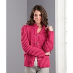 a woman standing in front of a door wearing a pink sweater