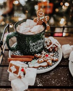 a cup of hot chocolate with marshmallows and gingerbread cookies on a plate