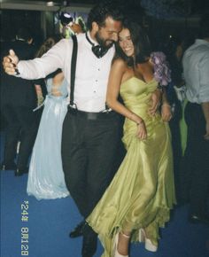 a man and woman are dancing together at a formal event with other people in the background