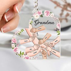 a hand holding a heart shaped keychain with the words grandma on it