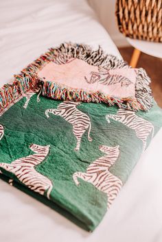 two blankets sitting on top of a bed next to a wicker basket and chair