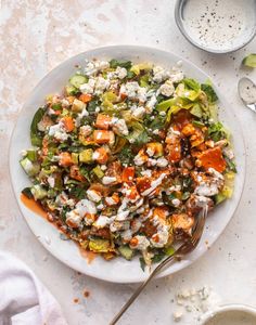 a white plate topped with a salad next to two cups of milk and spoons