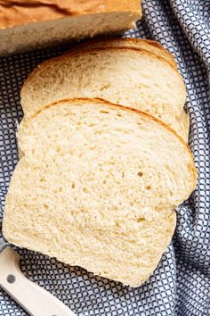 two slices of bread sitting on top of a blue and white cloth next to a knife