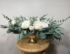 a vase filled with white flowers on top of a wooden table