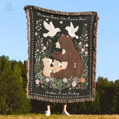 a woman standing in front of a bear and birds tapestry