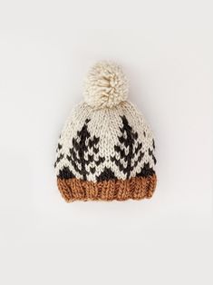 a white and brown knitted beanie with trees on it, against a white background