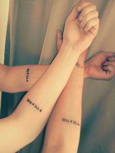 two people are holding hands with tattoos on their arms and both have words written on them