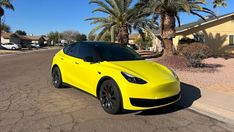 a yellow sports car parked in front of some palm trees