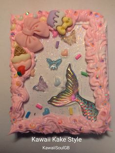 a pink cake decorated with sea animals and mermaid tailes on it's side