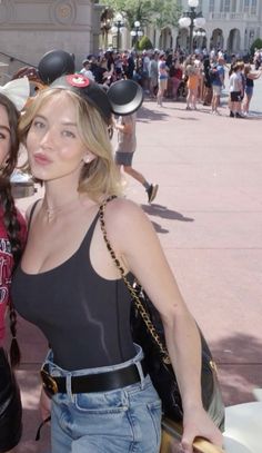 two women standing next to each other in front of mickey mouse ears