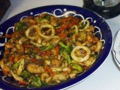 a blue plate topped with pasta and veggies on top of a white table