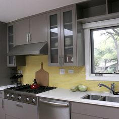 a kitchen with stainless steel appliances and yellow backsplashing on the windowsill