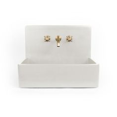 a pair of gold - plated earrings sits on a white stand