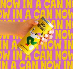 a hand holding a can of beer in front of a pink and yellow background with words