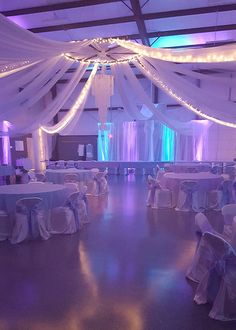 an indoor wedding venue with white draping and blue lights