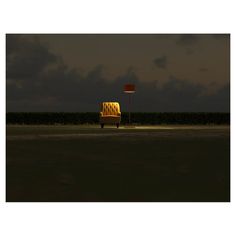 a yellow bench sitting in the middle of a field at night with a street light