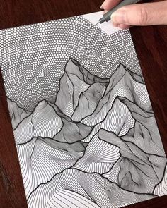 someone is drawing mountains on paper with a pen and inking the image in black and white