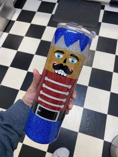 a hand holding a blue and red tumbler cup with a cartoon character on it