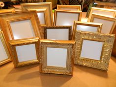 there are many gold colored frames on the table with one empty photo in front of them