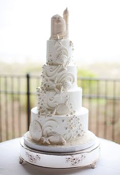 a white wedding cake with seashells on it