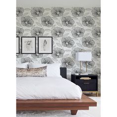 a bed with white sheets and pillows in front of a wallpapered bedroom area