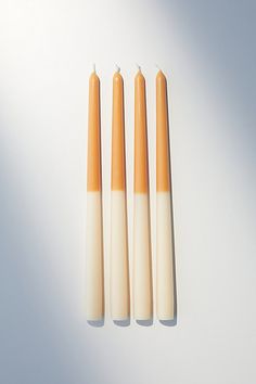 three candles sitting next to each other on top of a white surface with one candle in the middle