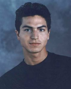 a young man in a black shirt posing for a photo with his eyes wide open