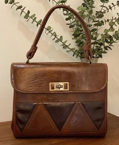 1960s 1970s Multi Brown Vinyl Top Handle Handbag, Vintage Purse, Retro Mod Purse Retro 1960s 1970s two tone brown vinyl/naugahyde top handle handbag with a diamond design on the front of the bag and a solid brown back. It features a single handle strap. Gold tone metal hardware with a twist closure that works well and closes tightly. Opens to a vinyl lining with a dividing metal zippered pocket. There are probably feet on the bottom of the bag. Vintage condition *the handbag presents well but does have a few cracks underneath the handle strap.  The exterior is immediately with no scratches or other issues.  At the dividing zippered pocket a seam has come loose but does not effect the pocket. The metal hardware shows normal age related issues. Priced accordingly. Measurements: Width x 10" a Handbag Vintage, Solid Brown, Top Handle Handbags, Vintage Purse, Chapel Hill, Bag Vintage, Diamond Design, Metal Hardware, Gold Tone Metal