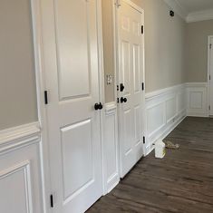 an empty room with white doors and hard wood flooring on the side of it